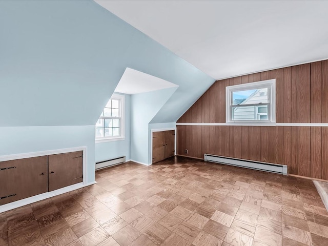 bonus room with lofted ceiling, baseboard heating, and wood walls