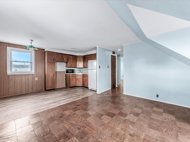 kitchen featuring white fridge, wood walls, and decorative backsplash