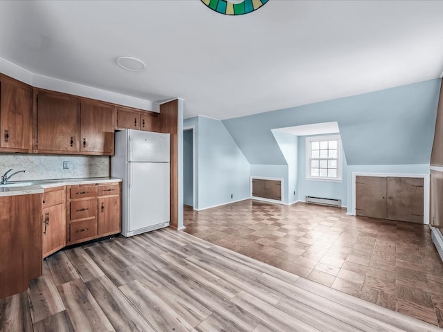 kitchen with vaulted ceiling, tasteful backsplash, a baseboard radiator, sink, and white refrigerator