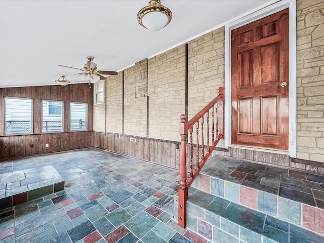 interior space featuring ceiling fan and wood walls