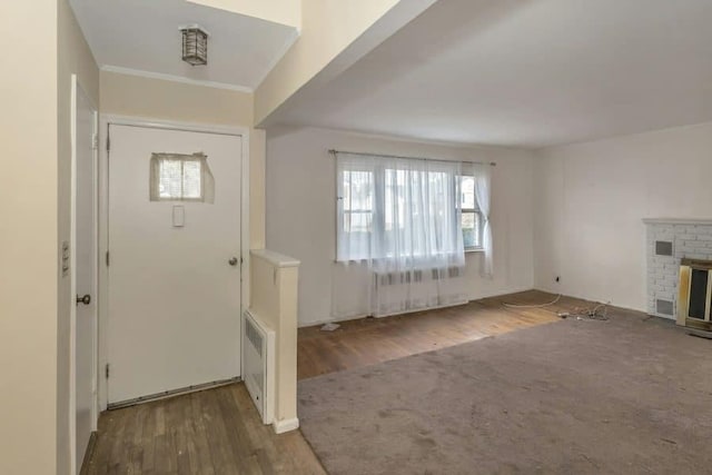 entryway featuring dark wood-type flooring, radiator heating unit, and a brick fireplace