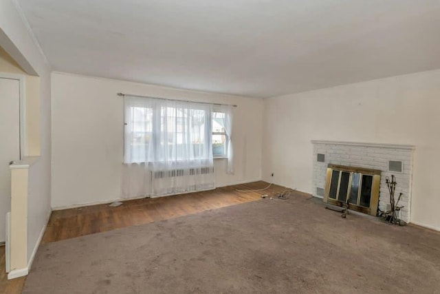 unfurnished living room featuring radiator, a fireplace, and hardwood / wood-style floors