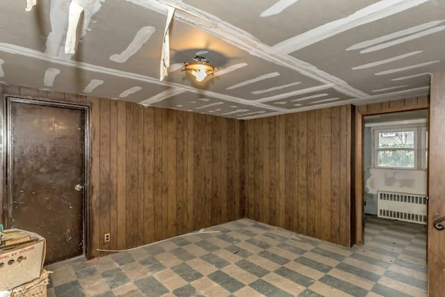 unfurnished bedroom with radiator, wooden walls, and ceiling fan