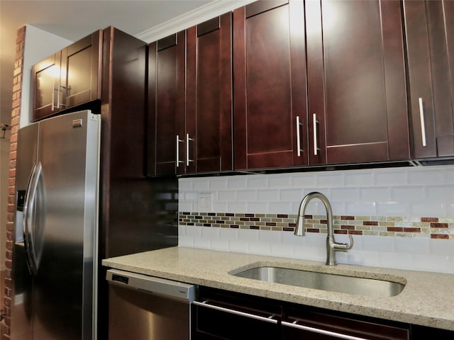 kitchen featuring stainless steel appliances, sink, light stone counters, and decorative backsplash