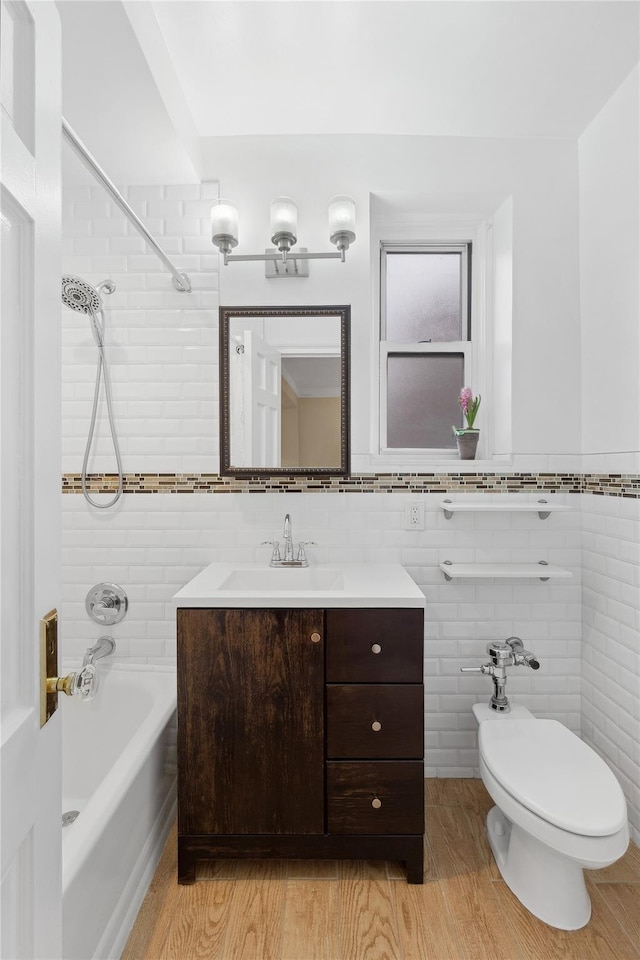 full bathroom featuring vanity, tiled shower / bath combo, tile walls, and toilet