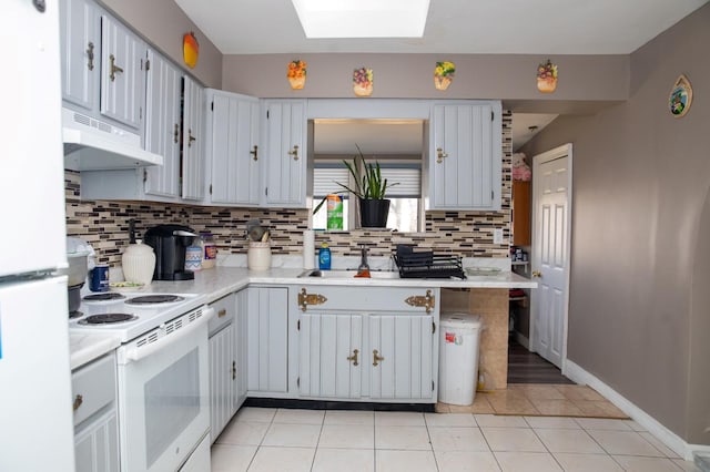 kitchen with a skylight, sink, decorative backsplash, light tile patterned floors, and white appliances