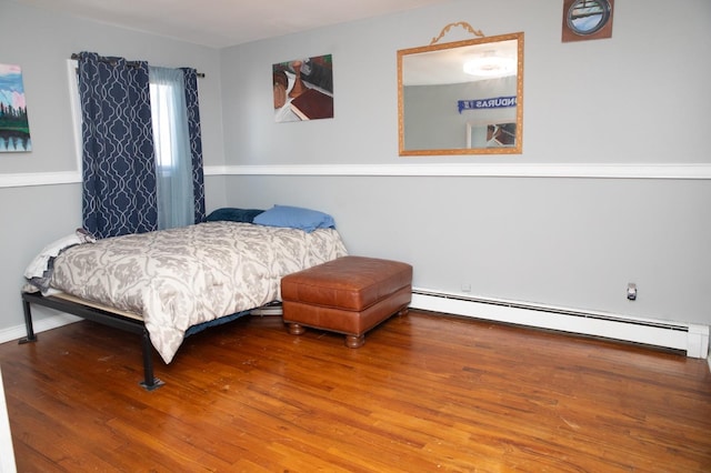 bedroom with a baseboard heating unit and hardwood / wood-style flooring