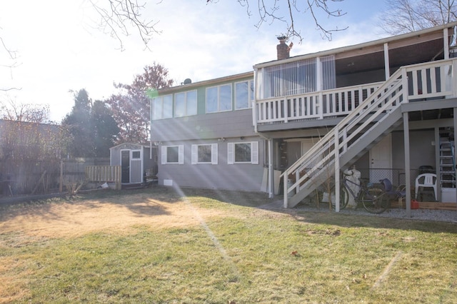 rear view of property featuring a storage shed, a deck, and a lawn