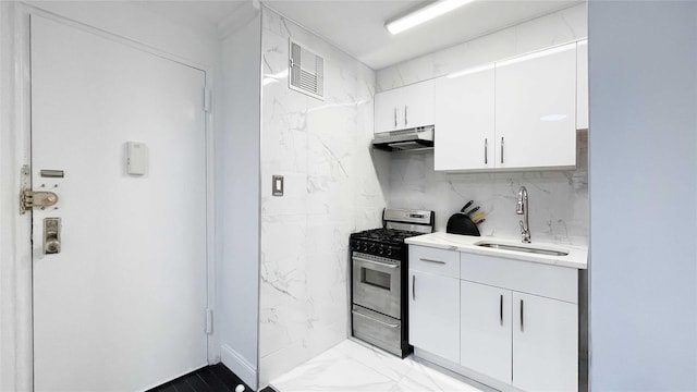 kitchen featuring white cabinetry, stainless steel gas range oven, sink, and tasteful backsplash