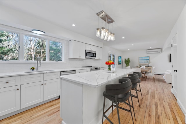 kitchen featuring stainless steel appliances, a center island, a wall mounted AC, and white cabinets