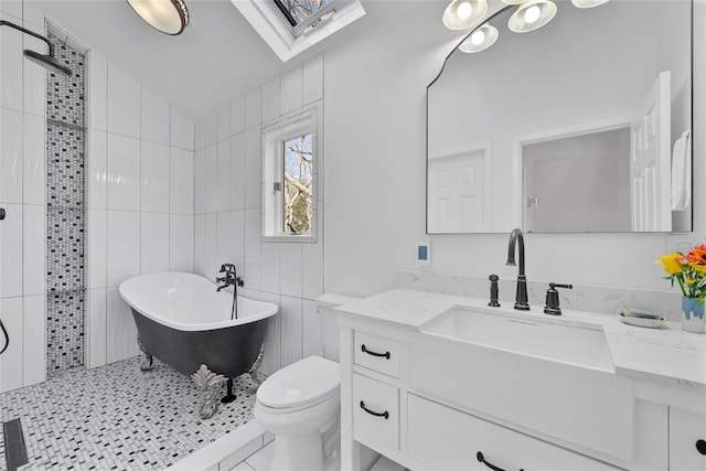 bathroom featuring a bathing tub, vaulted ceiling with skylight, tile walls, vanity, and toilet