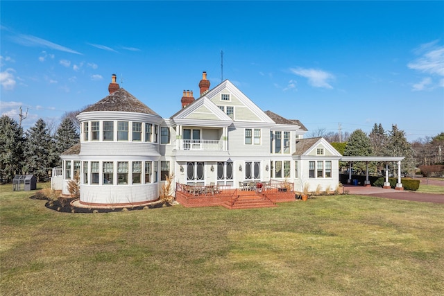 rear view of property featuring a lawn, a sunroom, and a carport