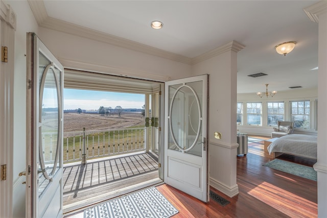 foyer with ornamental molding, hardwood / wood-style flooring, and a notable chandelier