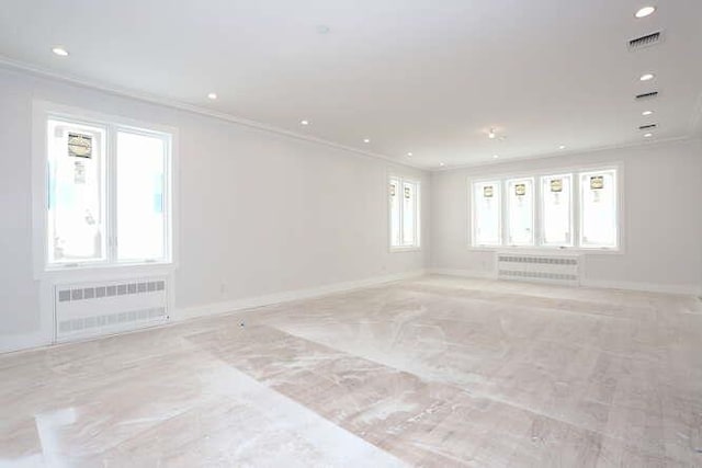 spare room with radiator heating unit, visible vents, and crown molding