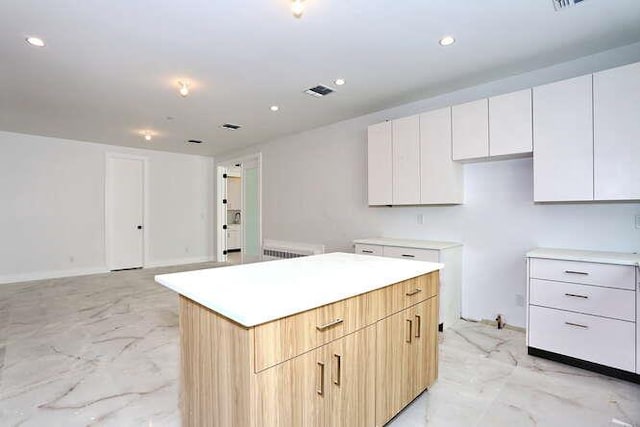 kitchen with marble finish floor, a center island, white cabinetry, and recessed lighting