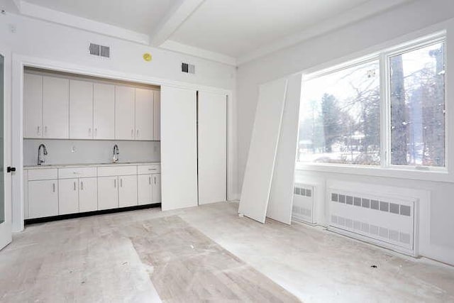 kitchen with a wealth of natural light, visible vents, a sink, and radiator heating unit