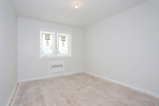 empty room featuring light wood-type flooring, visible vents, and baseboards