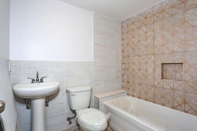 full bath with toilet, a sink, and tile walls