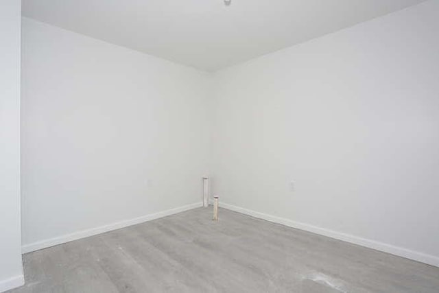 unfurnished room featuring baseboards and wood finished floors