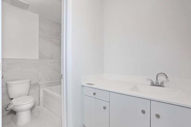 bathroom with toilet, a tub to relax in, and vanity