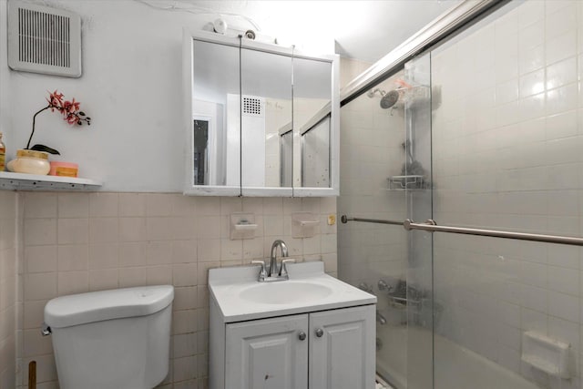 full bathroom with vanity, tile walls, enclosed tub / shower combo, and toilet