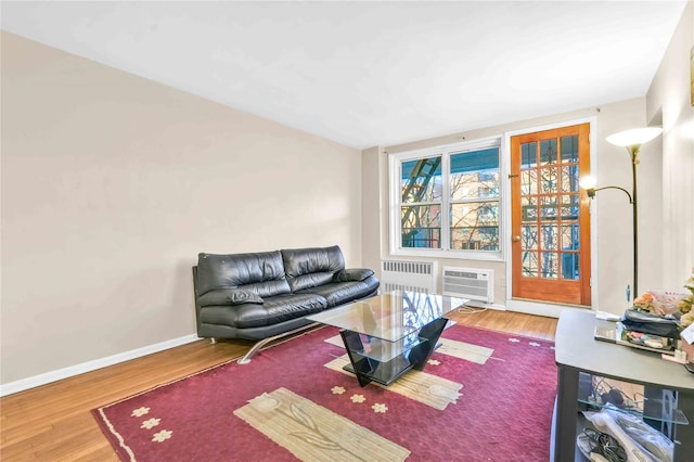 living room featuring radiator, wood-type flooring, and a wall unit AC