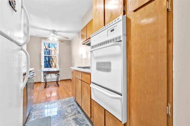 kitchen with ceiling fan, white appliances, and light hardwood / wood-style flooring