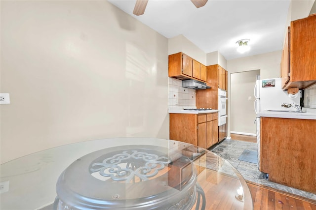 kitchen with sink, light hardwood / wood-style flooring, white appliances, and decorative backsplash