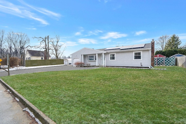 rear view of house with a lawn and solar panels