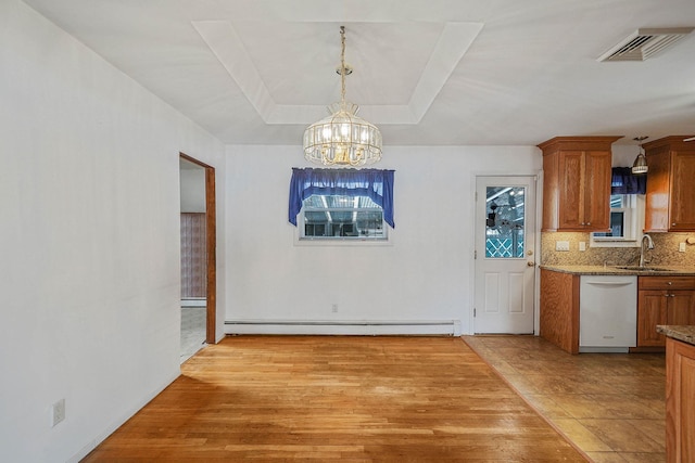 unfurnished dining area featuring sink, an inviting chandelier, a baseboard heating unit, a raised ceiling, and light wood-type flooring