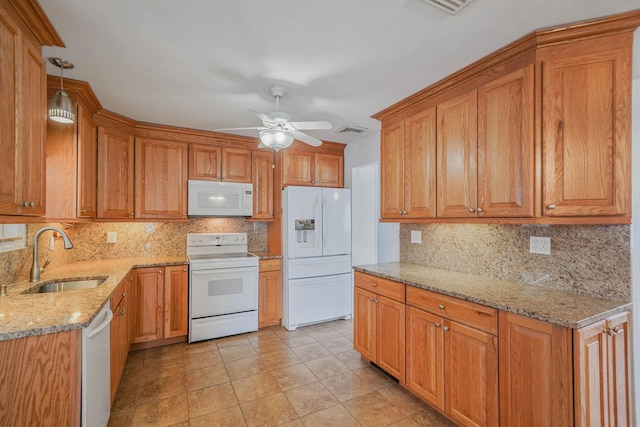 kitchen with sink, light stone counters, tasteful backsplash, decorative light fixtures, and white appliances