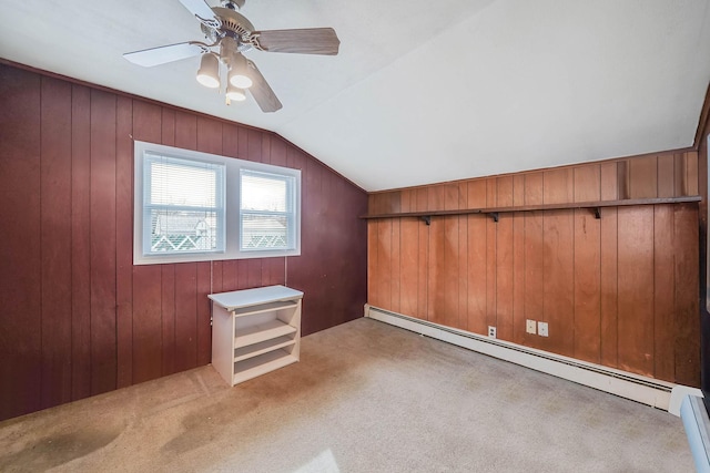 additional living space with lofted ceiling, wooden walls, carpet flooring, ceiling fan, and a baseboard heating unit