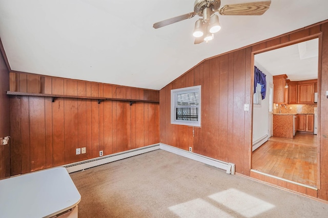 additional living space featuring ceiling fan, baseboard heating, wooden walls, light carpet, and vaulted ceiling