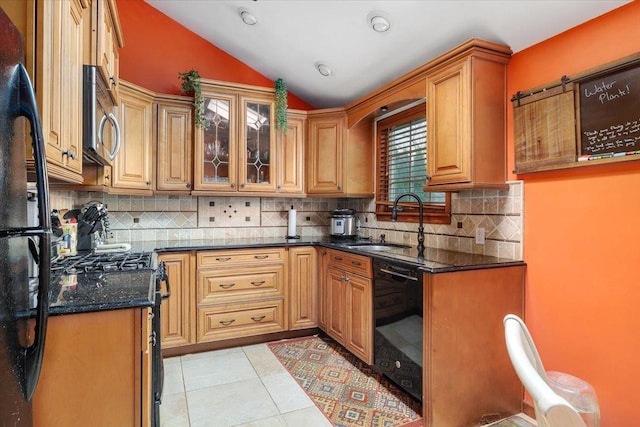 kitchen with lofted ceiling, sink, light tile patterned floors, black appliances, and dark stone counters