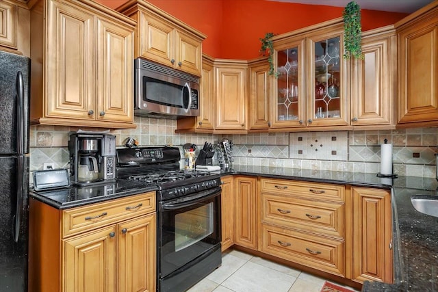 kitchen featuring dark stone counters, light tile patterned floors, and black appliances