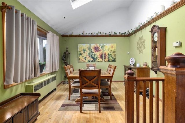 dining area with lofted ceiling with skylight, radiator, and light wood-type flooring