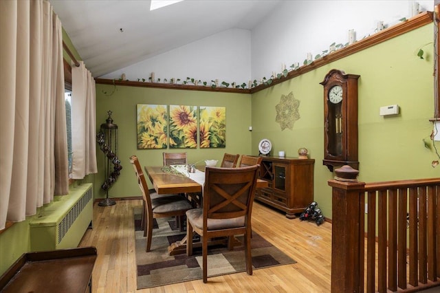 dining area with radiator heating unit, lofted ceiling, and hardwood / wood-style floors