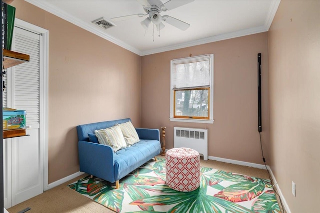 living area with radiator, ornamental molding, ceiling fan, and carpet