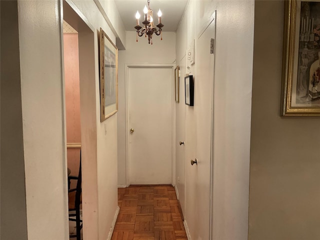 hall with dark parquet flooring and a chandelier