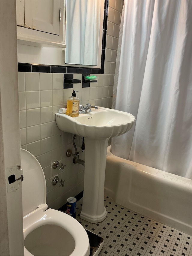 bathroom featuring toilet, tile patterned flooring, and tile walls