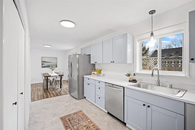 kitchen featuring pendant lighting, sink, stainless steel appliances, and gray cabinetry