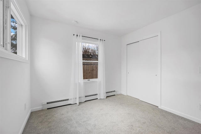 unfurnished bedroom featuring light colored carpet, baseboard heating, and a closet