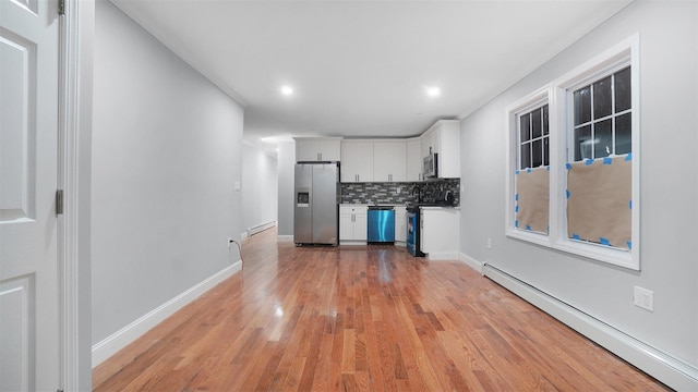 kitchen featuring stainless steel appliances, white cabinetry, tasteful backsplash, and baseboard heating