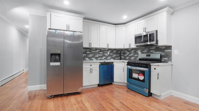 kitchen featuring crown molding, white cabinets, stainless steel appliances, light hardwood / wood-style floors, and backsplash