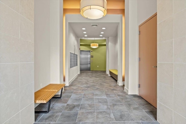 hallway featuring elevator and tile walls