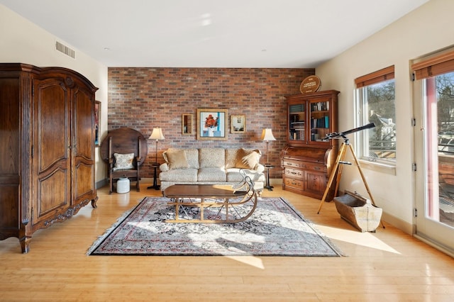 living room with brick wall and light hardwood / wood-style flooring