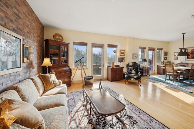 living room with brick wall and light hardwood / wood-style flooring