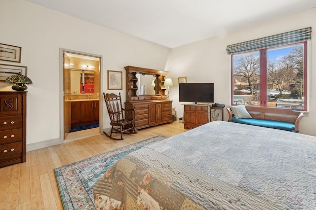 bedroom with connected bathroom and light wood-type flooring