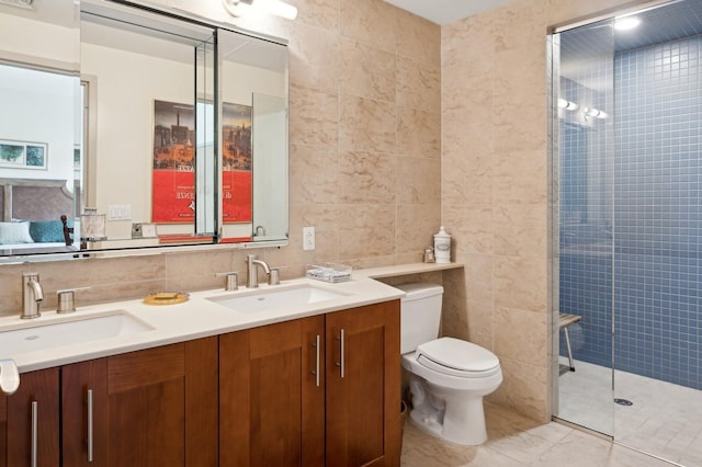 bathroom featuring tiled shower, vanity, toilet, and tile walls