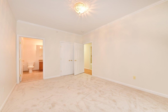 unfurnished bedroom featuring ensuite bath, ornamental molding, carpet flooring, and a closet